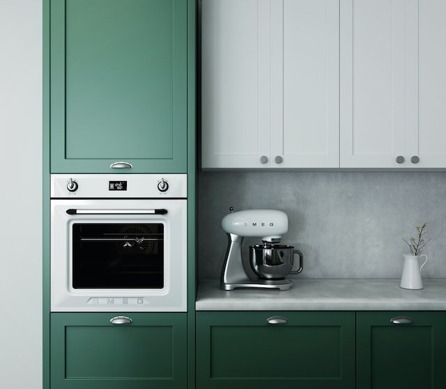 Kitchen interior with green and white cabinets, an oven, and a stand mixer