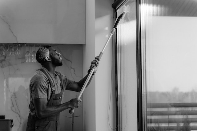 black and white photo of person vaccuuming curtains