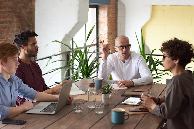 people holding a meeting at a wooden table