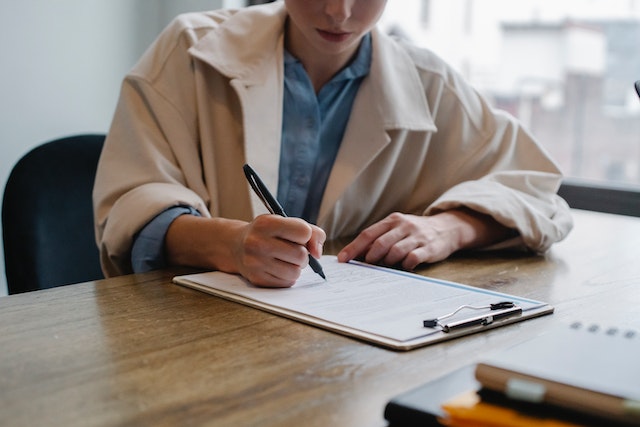 person writing on a clipboard in an office