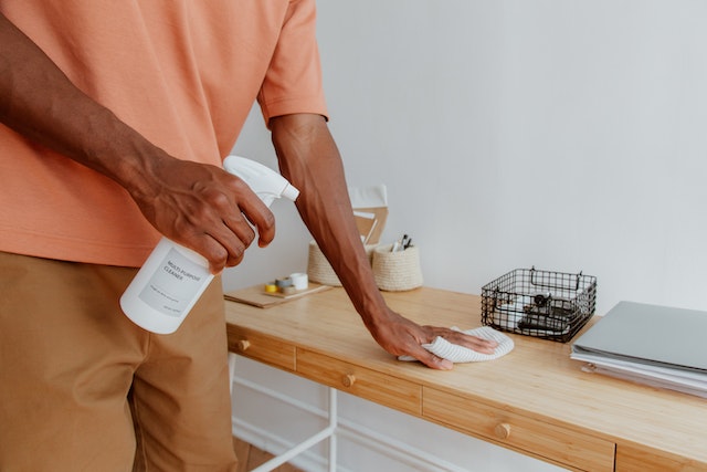 person in salmon coloured shirt cleaning off desk