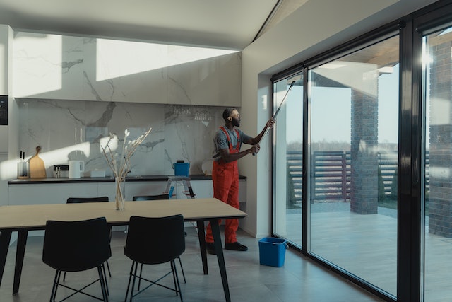 person in orange overalls cleaning window