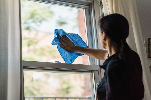 person cleaning a window with a blue rag