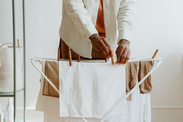 person hanging laundry on a small drying rack with clothespins 