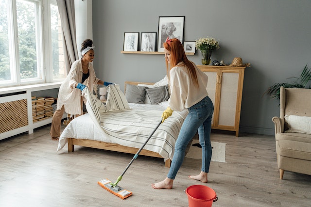 two people cleaning a bedroom