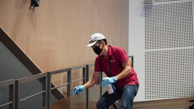 person cleaning class staircase rails