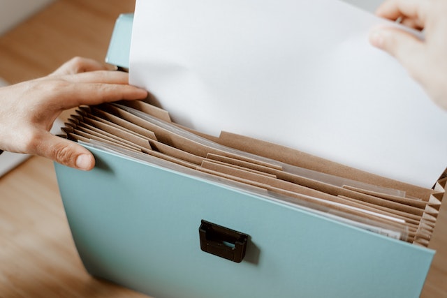 person putting papers into accordion file