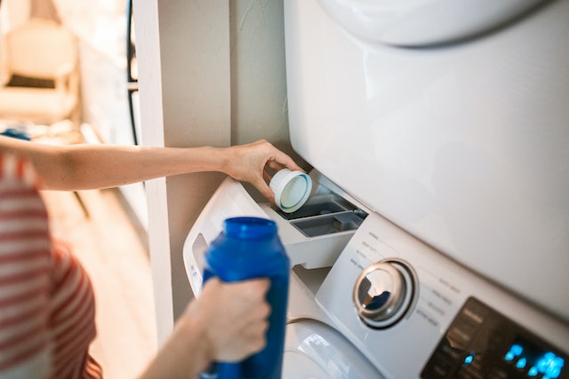 person pouring detergent into washing machine